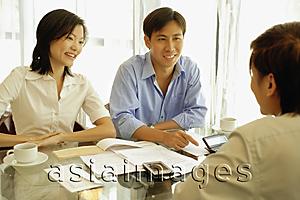 Asia Images Group - Three people sitting at table, face to face