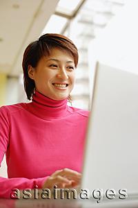 Asia Images Group - Young woman using laptop, smiling