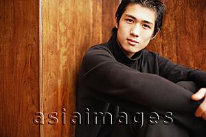 Asia Images Group - Young man sitting on floor, hugging knees