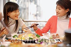 Asia Images Group - Young women eating at Chinese restaurant, side by side