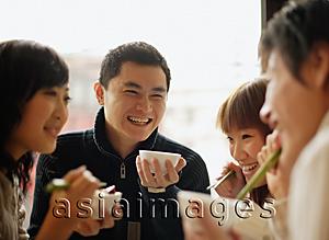 Asia Images Group - Group of friends eating at a Chinese restaurant, side by side
