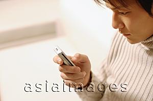 Asia Images Group - Young man sitting, using mobile phone