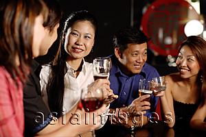 Asia Images Group - Friends having drinks at bar, sitting in a row