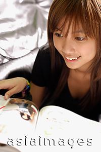 Asia Images Group - Young woman flipping through magazine, smiling