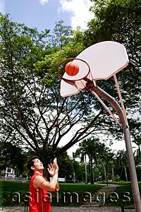 Asia Images Group - Man shooting basketball through a hoop