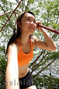 Asia Images Group - Woman holding on to rope on a jungle gym, low angle view