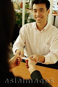 Asia Images Group - Two executives sitting across desk, exchanging business card