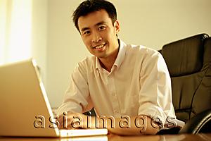 Asia Images Group - Executive using laptop, looking at camera