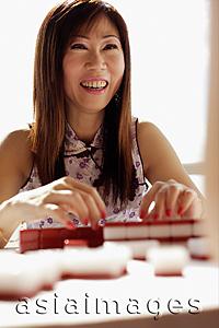 Asia Images Group - Woman playing mahjong, smiling