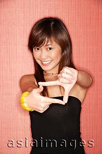 Asia Images Group - Young woman making hand sign, looking at camera