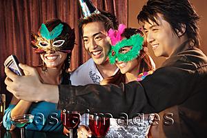 Asia Images Group - Couples with mask and hat using camera phone to take a picture