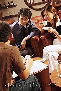 Asia Images Group - Young executives having a meeting in a cafe, woman drinking coffee
