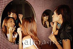 Asia Images Group - Young women putting on make-up in washroom
