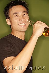 Asia Images Group -  Young man raising beer bottle