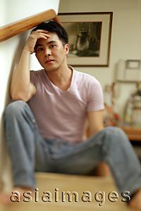 Asia Images Group - Man sitting on staircase, hand on head