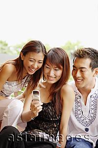 Asia Images Group - Young women and young man looking at mobile phone, smiling