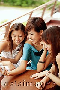 Asia Images Group - Young women smiling, looking at mobile phone