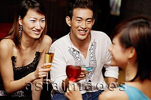 Asia Images Group - Couple holding drinks, facing another young woman