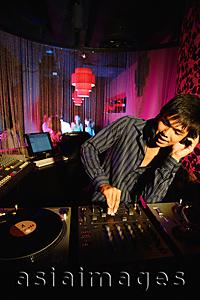 Asia Images Group - Young man spinning at club, using headphones