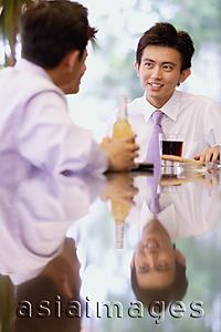 Asia Images Group - Young men sitting at bar counter with drinks