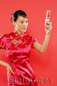 Asia Images Group - Woman holding mobile phone, hand on hip