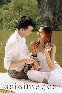 Asia Images Group - Couple sitting by a lake, with wine bottle and wine glass