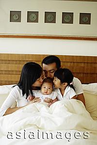 Asia Images Group - Father, mother and daughter kissing baby daughter