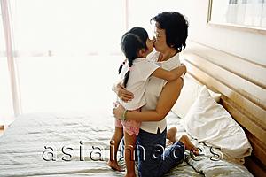 Asia Images Group - Granddaughter kissing grandmother on bed