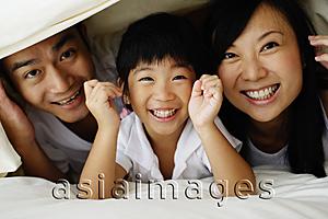 Asia Images Group - Couple with young daughter, hiding under bed sheets, looking at camera