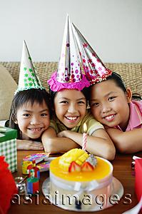 Asia Images Group - Three girls with party hats in front of birthday cake