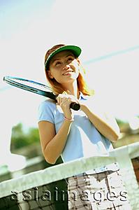 Asia Images Group - Woman holding tennis racket, looking away