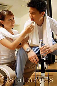 Asia Images Group - Couple in gym, resting, woman wiping man's face with towel