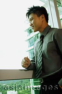 Asia Images Group - Businessman looking out window, smiling