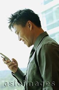 Asia Images Group - Businessman holding mobile phone, text messaging