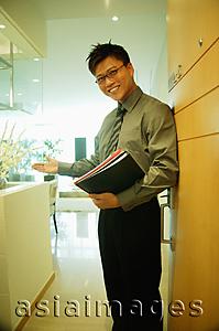 Asia Images Group - Executive carrying documents, looking at camera, arm outstretched