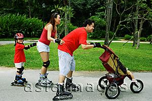 Asia Images Group - Family wearing roller blades, skating all in a row, father pushing stroller