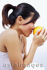 Asia Images Group - Woman smelling orange, sideview