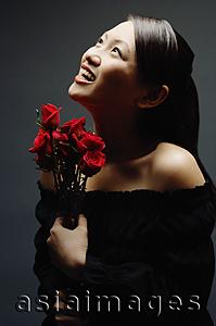 Asia Images Group - Young woman with bouquet of flowers, looking up