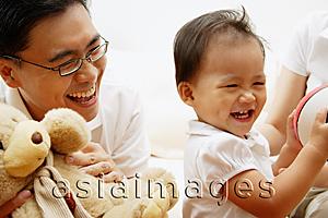 Asia Images Group - Young girl smiling, father next to her holding stuffed toy