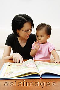 Asia Images Group - Mother with daughter, reading storybook