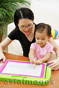 Asia Images Group - Mother with daughter, drawing on magnetic block