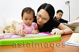 Asia Images Group - Mother and daughter drawing, father sitting and reading newspaper