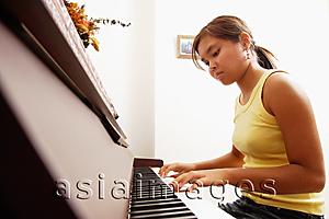 Asia Images Group - Young woman sitting at piano, looking down