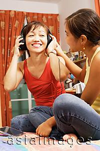 Asia Images Group - Mother and daughter side by side, mother listening to headphones