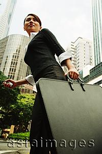 Asia Images Group - Business woman walking with briefcase, buildings in the background