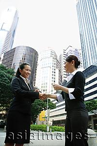 Asia Images Group - Two business women shaking hands, one holding business card
