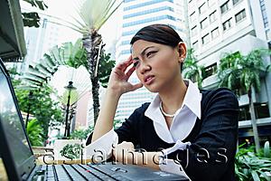 Asia Images Group - Business woman using laptop, frowning, hand on head