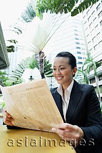 Asia Images Group - Business woman reading newspaper