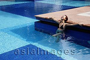 Asia Images Group - Young woman in swimming pool, leaning on edge of pool