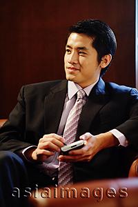 Asia Images Group - Young businessman holding PDA, looking away